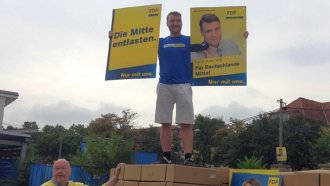 Patrick Kurth auf einer Ladefläche mit Kartons voller Wahlplakate